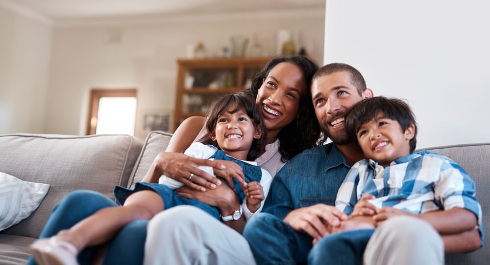 Happy, TV and parents with kids in home for bonding, relax and watching movies in living room on sofa