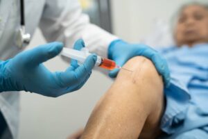 Asian doctor inject Hyaluronic acid platelet rich plasma into the knee of senior woman