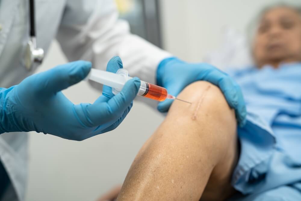 Asian doctor inject Hyaluronic acid platelet rich plasma into the knee of senior woman
