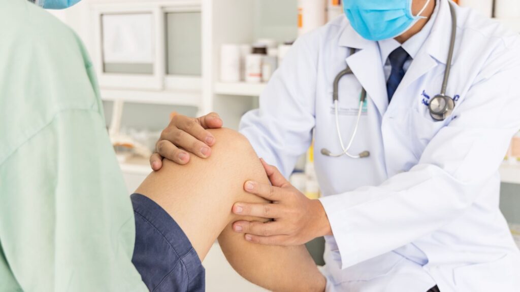 The orthopedic doctor or surgeon in white gown examined the patient with knee pain problem