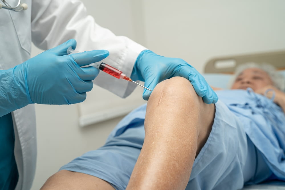 Asian doctor inject Hyaluronic acid platelet rich plasma into the knee of senior woman to walk without pain.