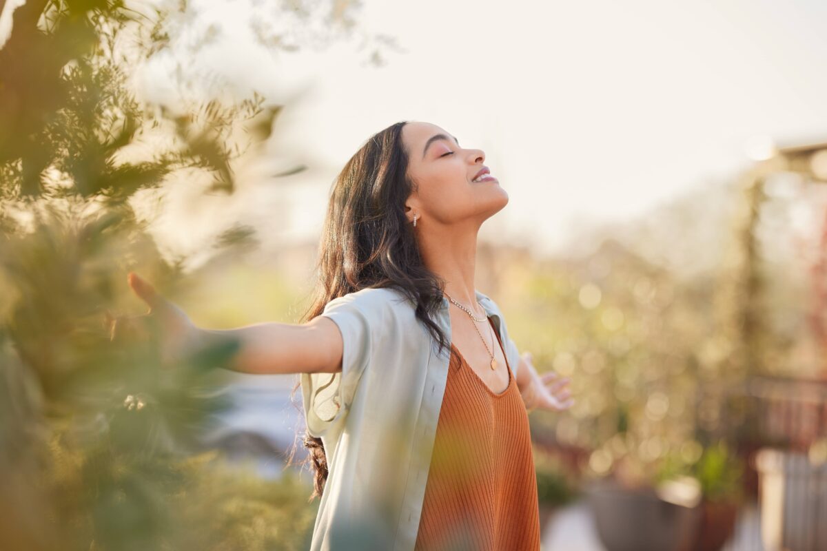 Young Latin woman with arms outstretched breathing in fresh air during sunrise