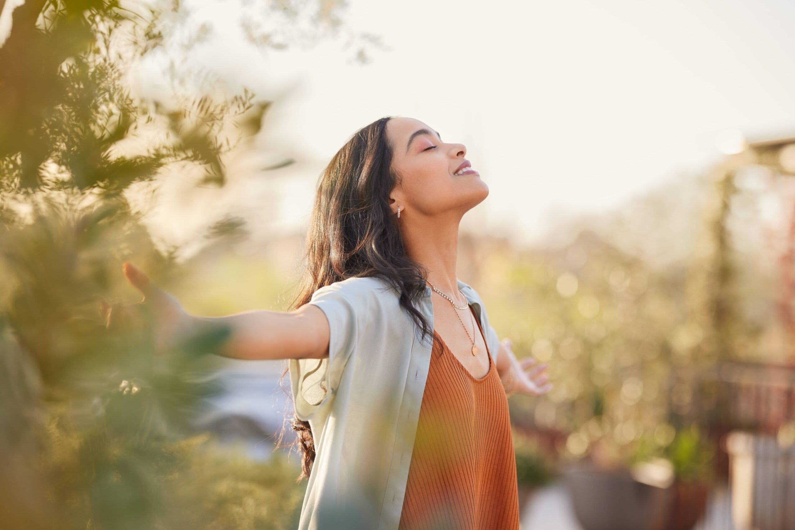 Young Latin woman with arms outstretched breathing in fresh air during sunrise