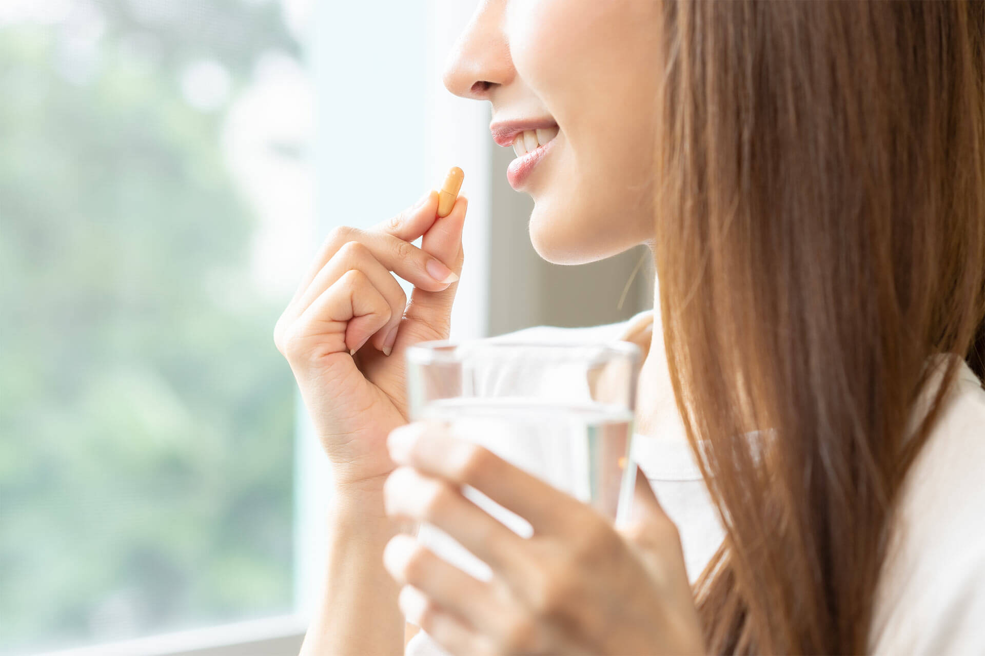 woman taking pill with glass of water