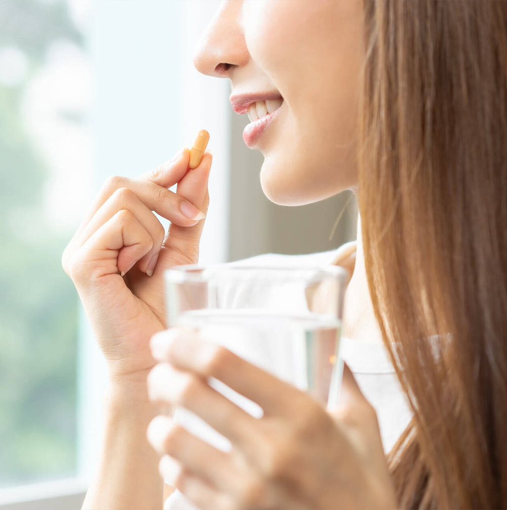woman taking pill with glass of water