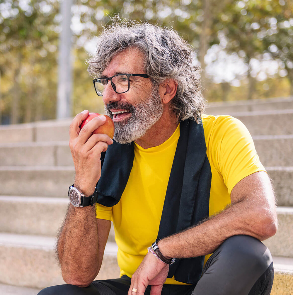 senior man rests eating an apple after workout