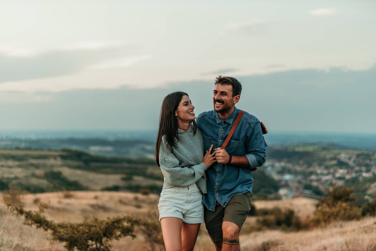A smiling couple walking and enjoying a quiet moment together in a vast meadow