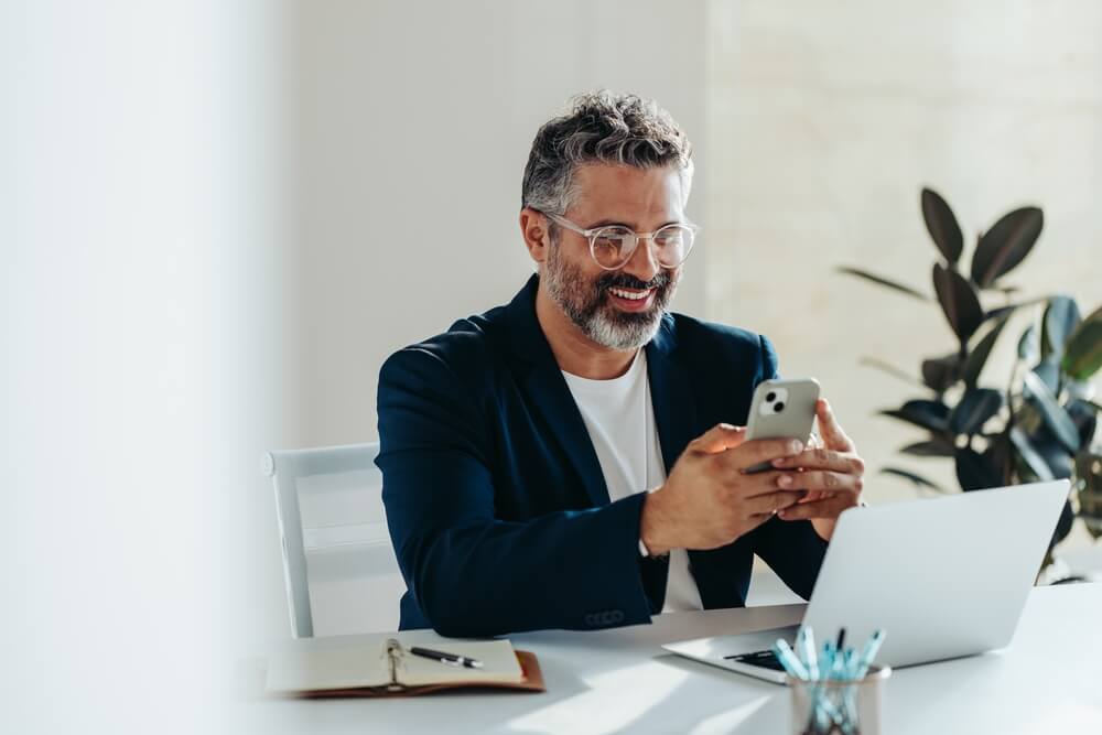 Cheerful, mature professional man is engrossed in his smartphone