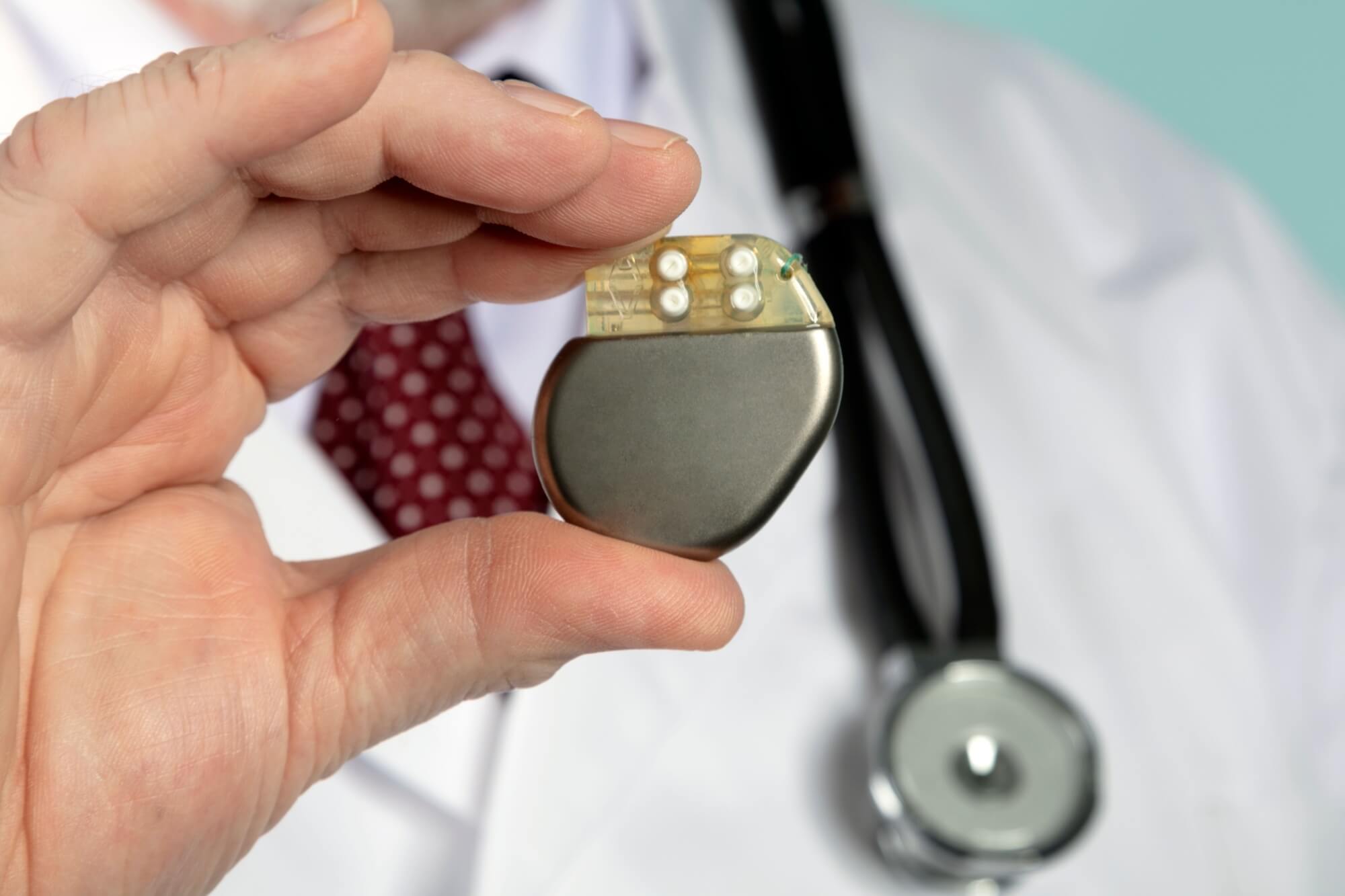 Male Hand hold Pacemaker in front of camera with blue background