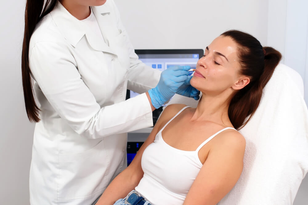 cosmetologist makes markings on the patient’s face