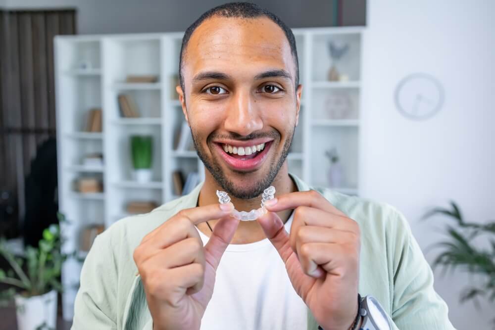 Adult man putting transparent braces for dental correction