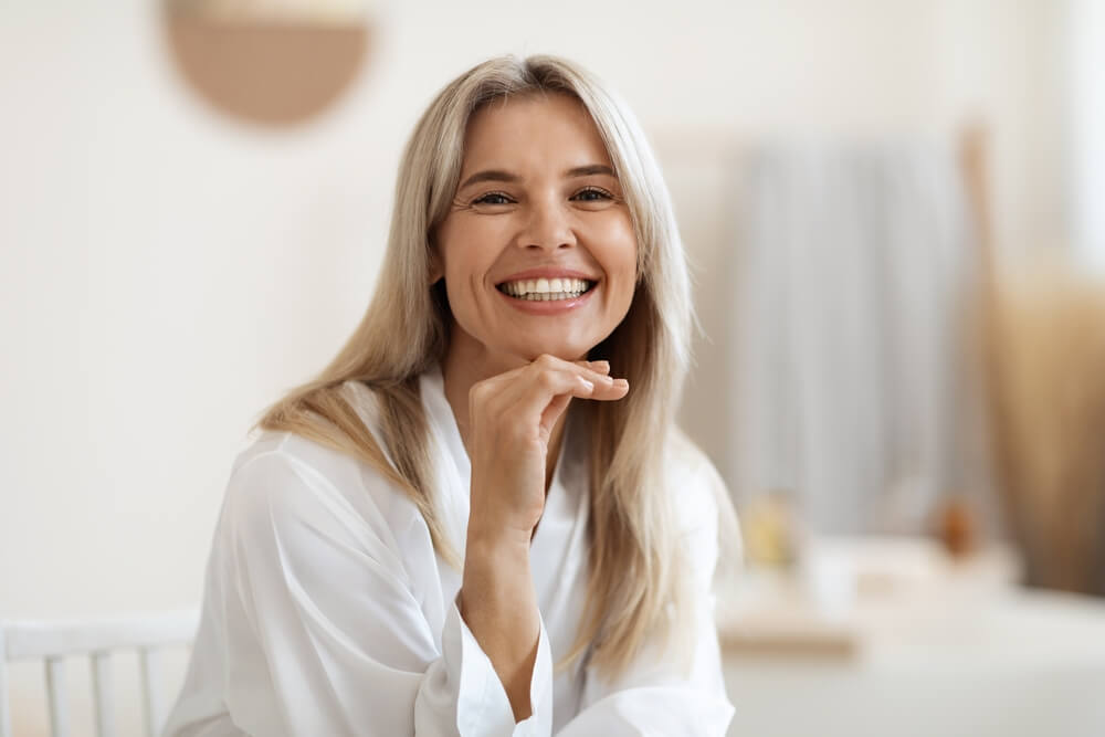 Happy attractive woman in white silky bathrobe