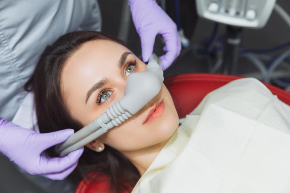 dentist puts inhalation sedative mask on his patient