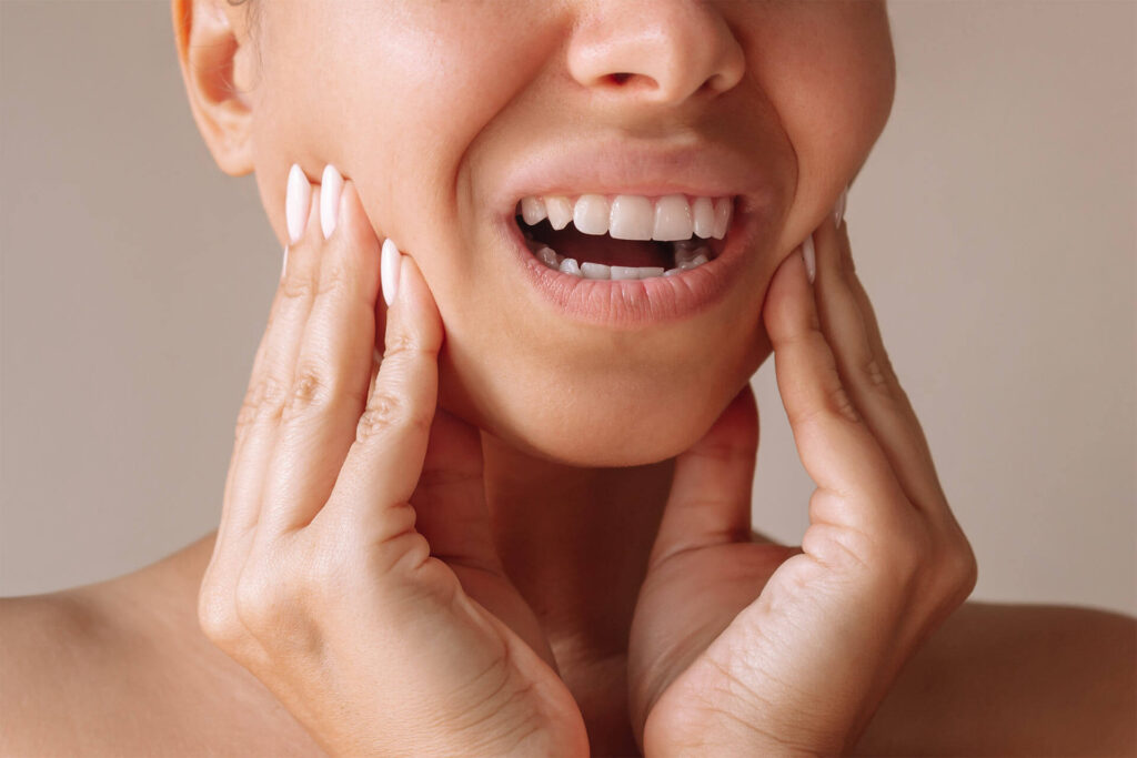 young woman suffering from jaw pain touching it with hands