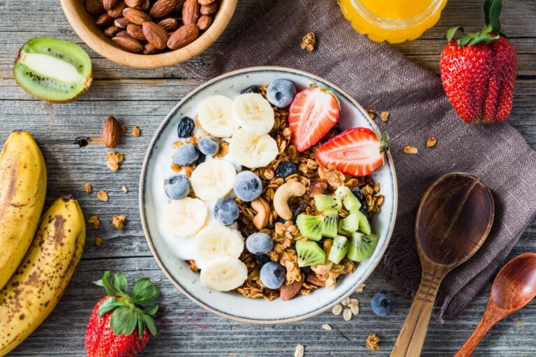 Homemade granola with nuts and raisins, kiwi, blueberries, banana, strawberries and plain yogurt