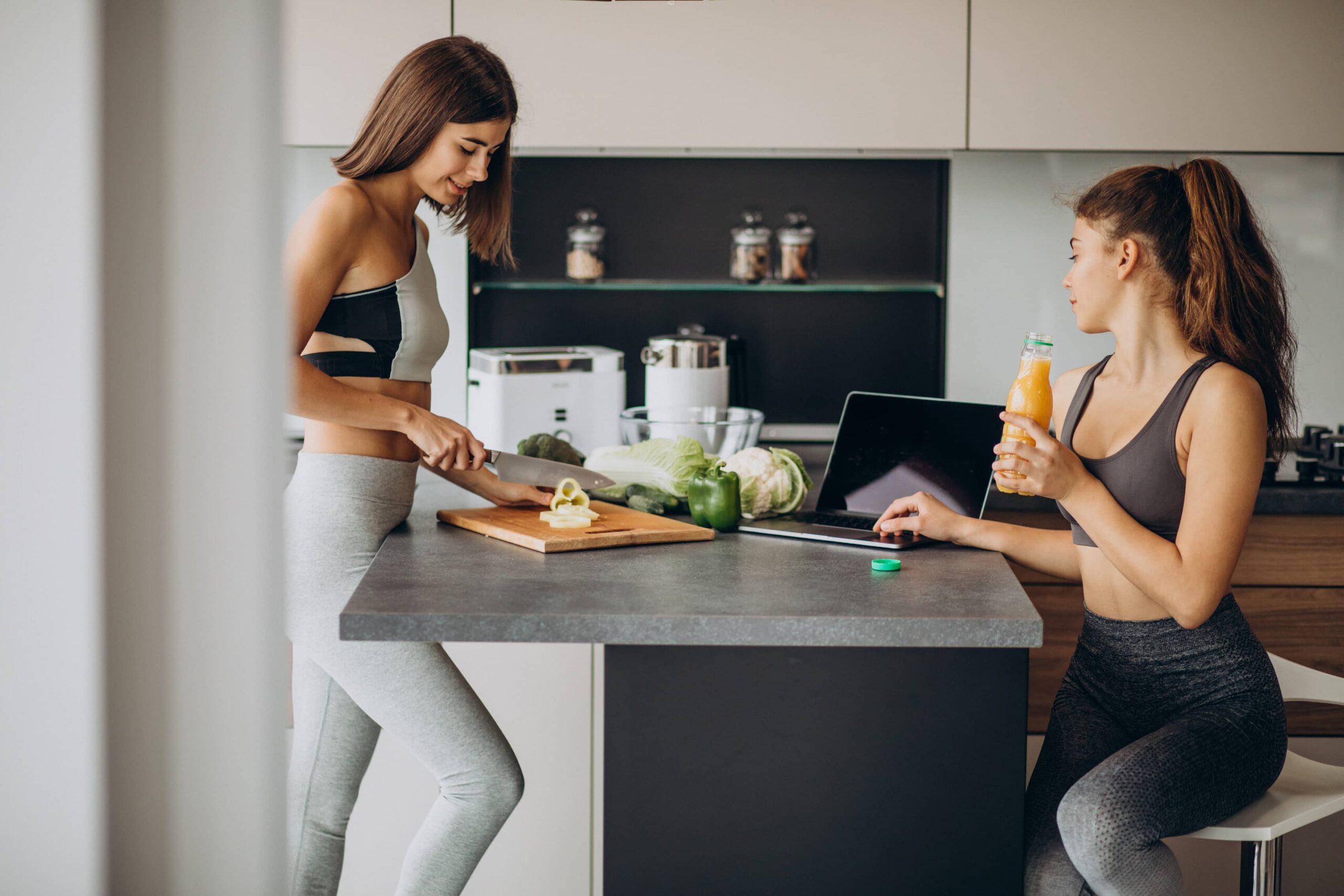 Two sporty girls at kitchen preparing food