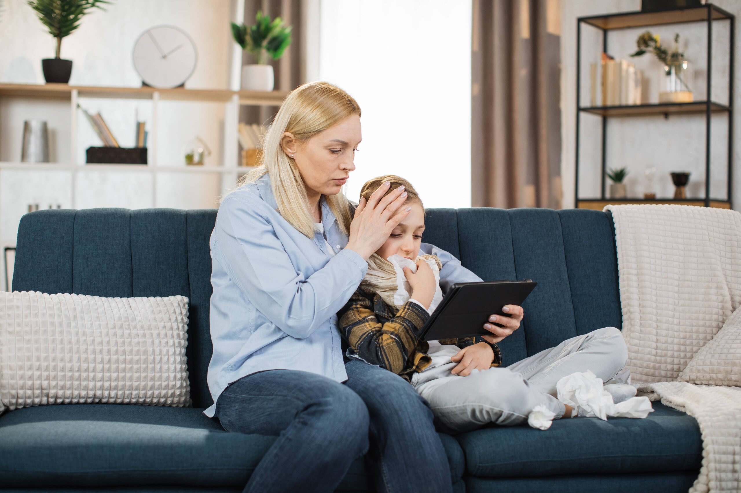 Pretty 40-aged woman mother sitting with her sick teen boy on soft sofa and watching together