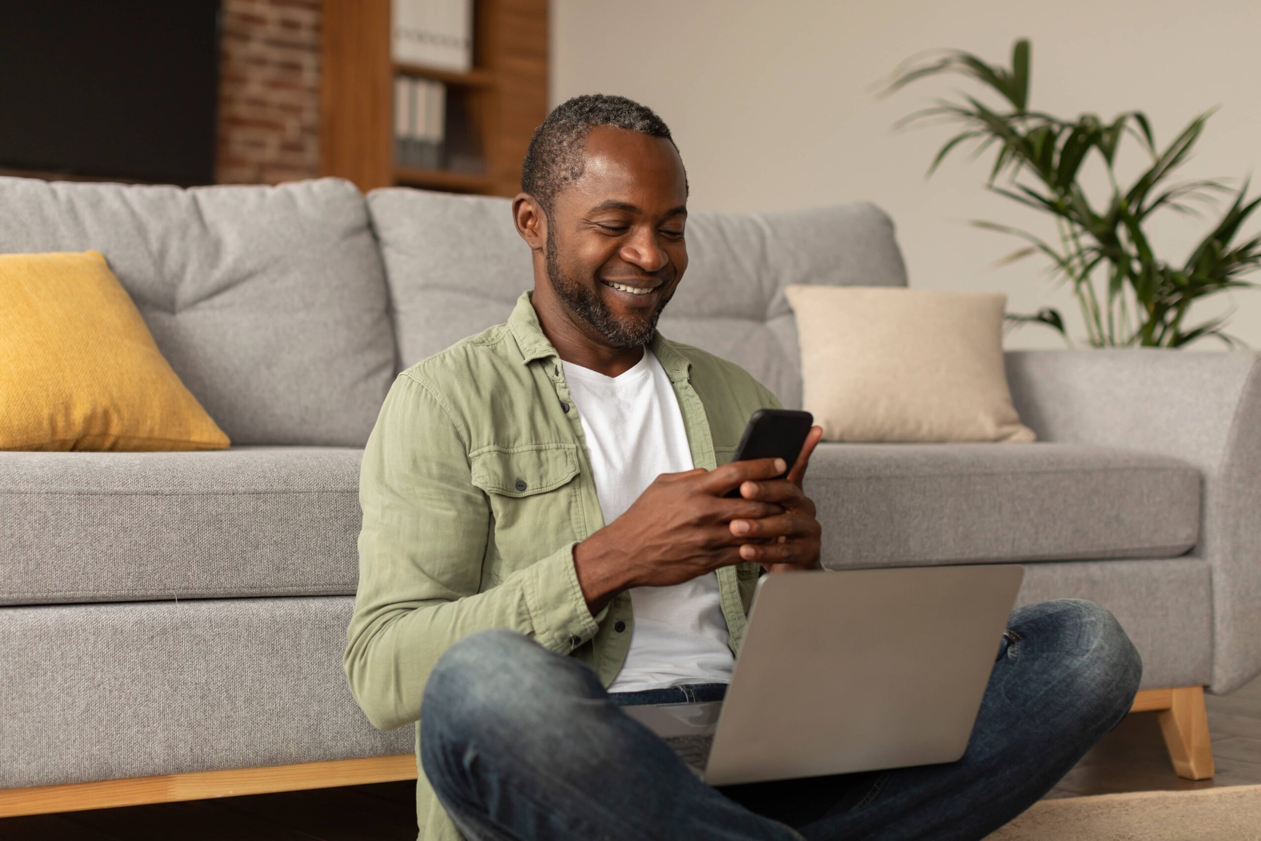 App for work, business remote. Happy middle aged african american male with laptop typing on phone