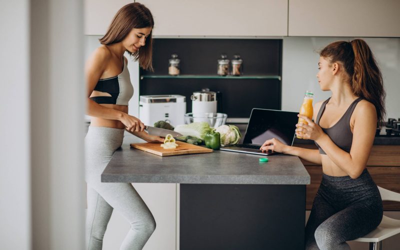 Two sporty girls at kitchen preparing food