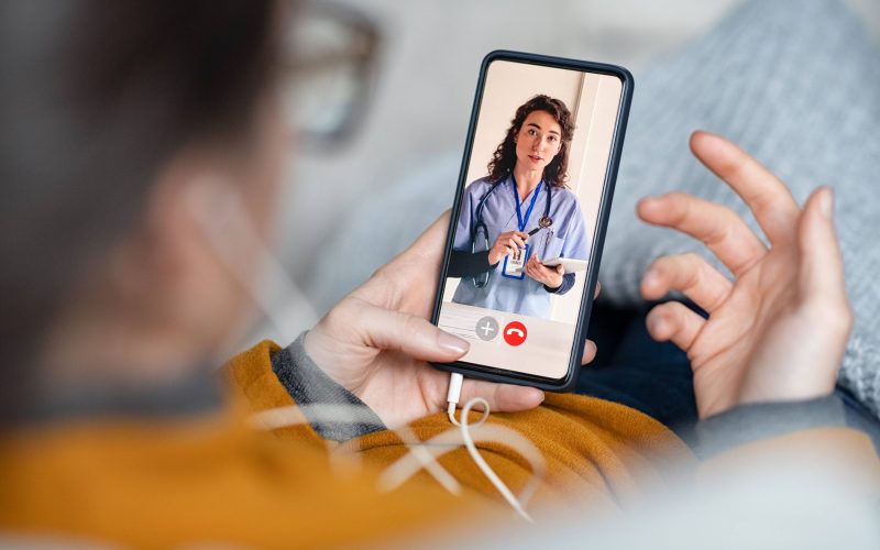 Young woman patient in conversation with specialist over video conferencing using smart phone