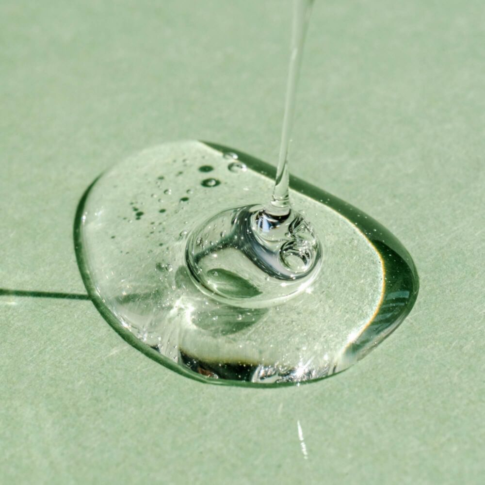A drop of transparent cosmetic gel on a green background.