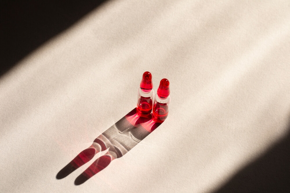 Liquid ampoules with vitamin B12 on a gray background. Pink liquid for injections.