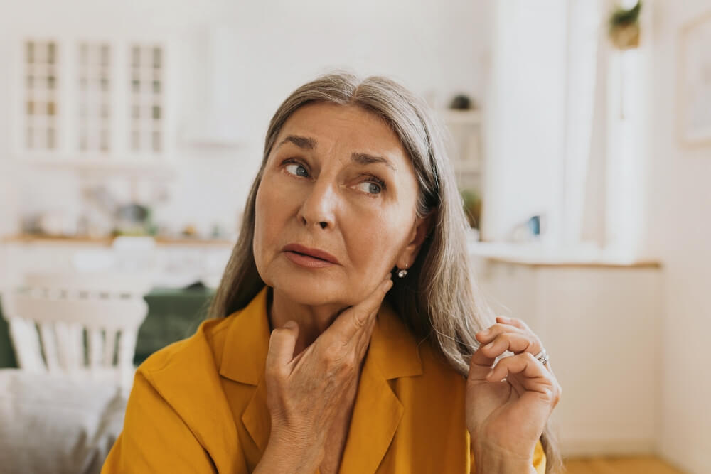 Elderly woman feeling pain, swollen thyroid or lymph nodes