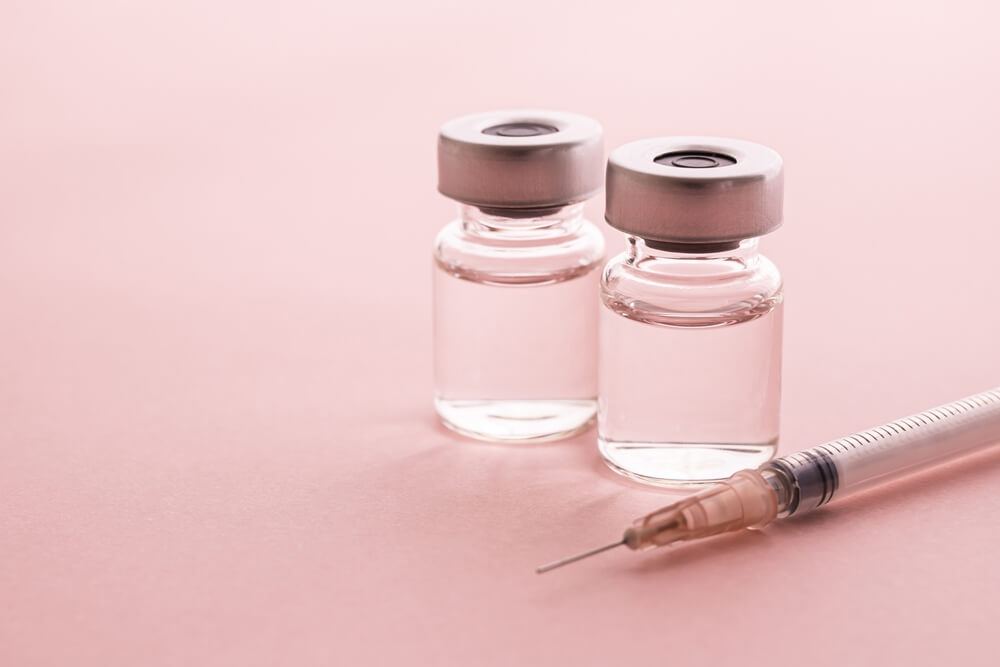 Syringe and vial on pink background. Image of cosmetic medicine and cosmetic surgery.