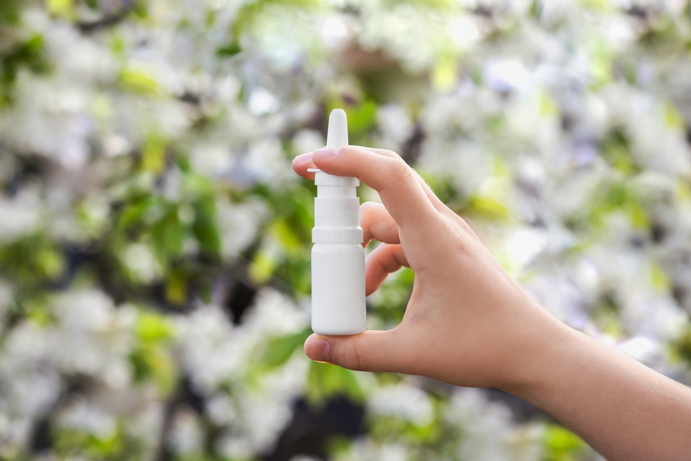 Nasal Spray for Allergies on Flowering Blooming Tree Spring Background