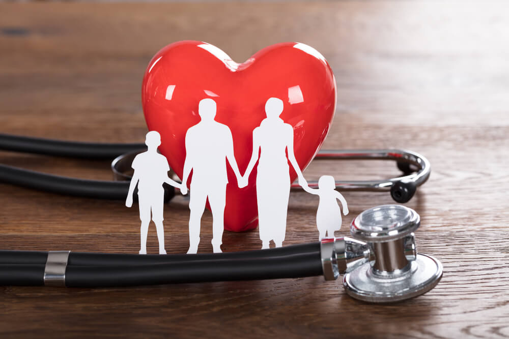 Family Cut-out And Stethoscope On Wooden Desk