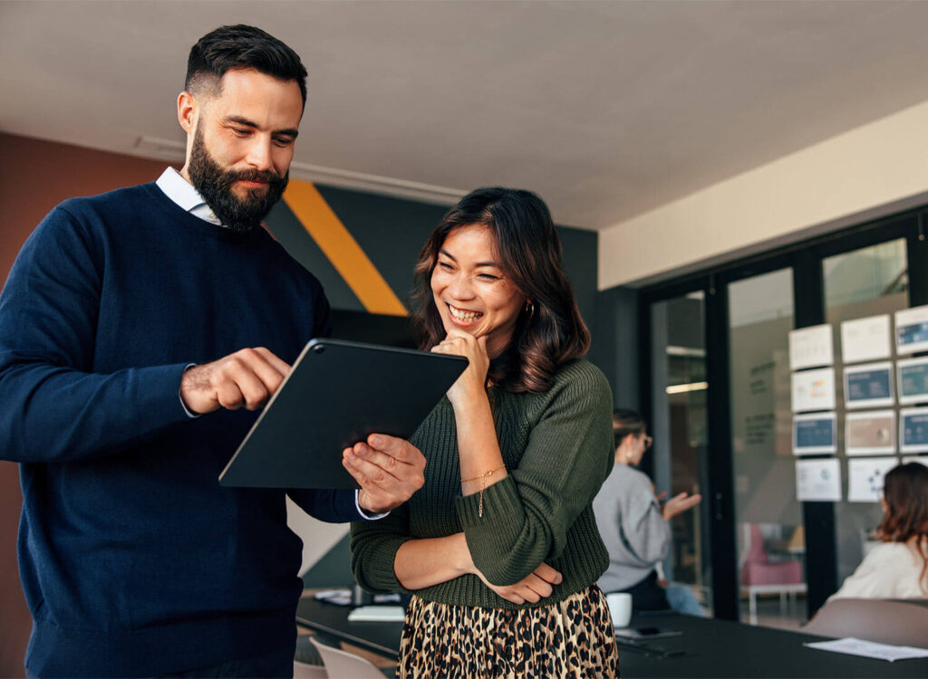 Happy colleagues using a digital tablet in a boardroom