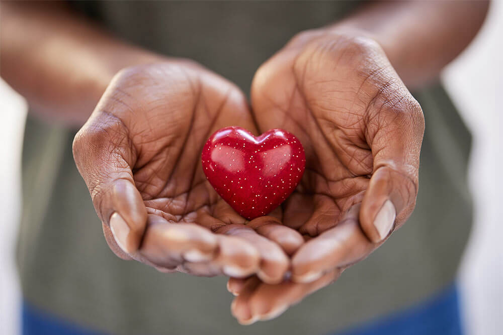 Woman hands holding a small red heart