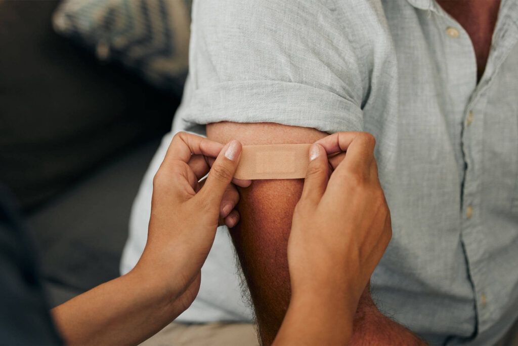 Plaster with hands of a doctor sticking a bandaid on a patient in the hospital