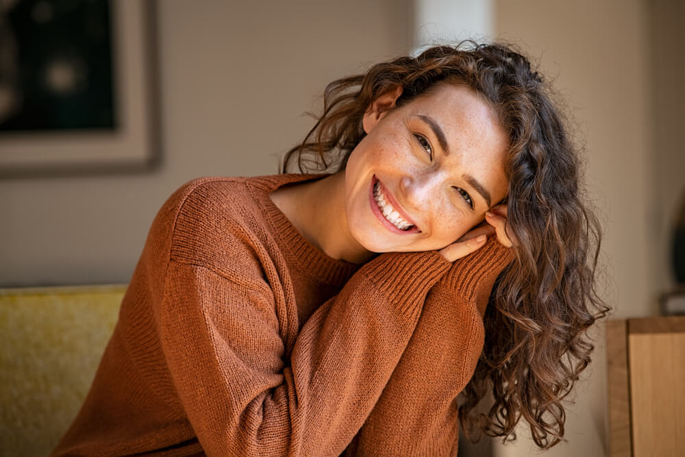 Happy young woman sitting on sofa at home
