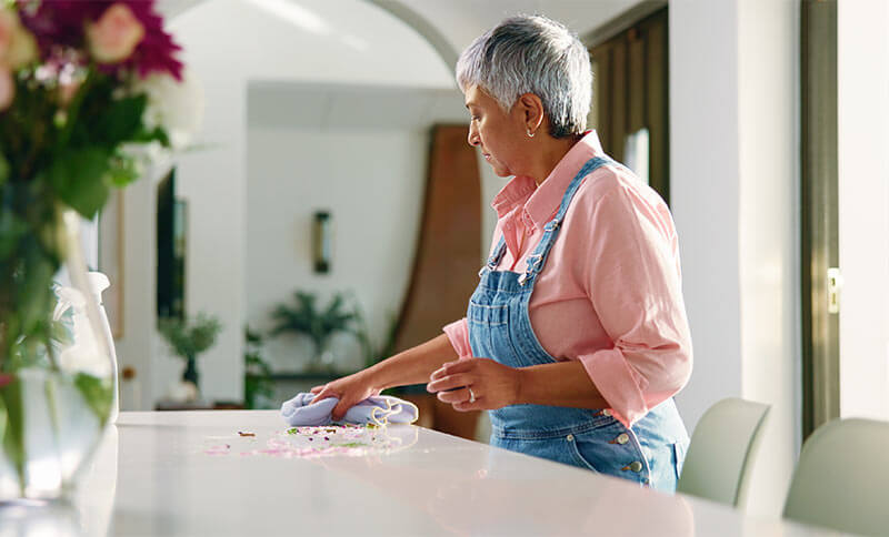 Mature woman, cleaning and wipe table in home for housekeeping, chores or hygiene maintenance.