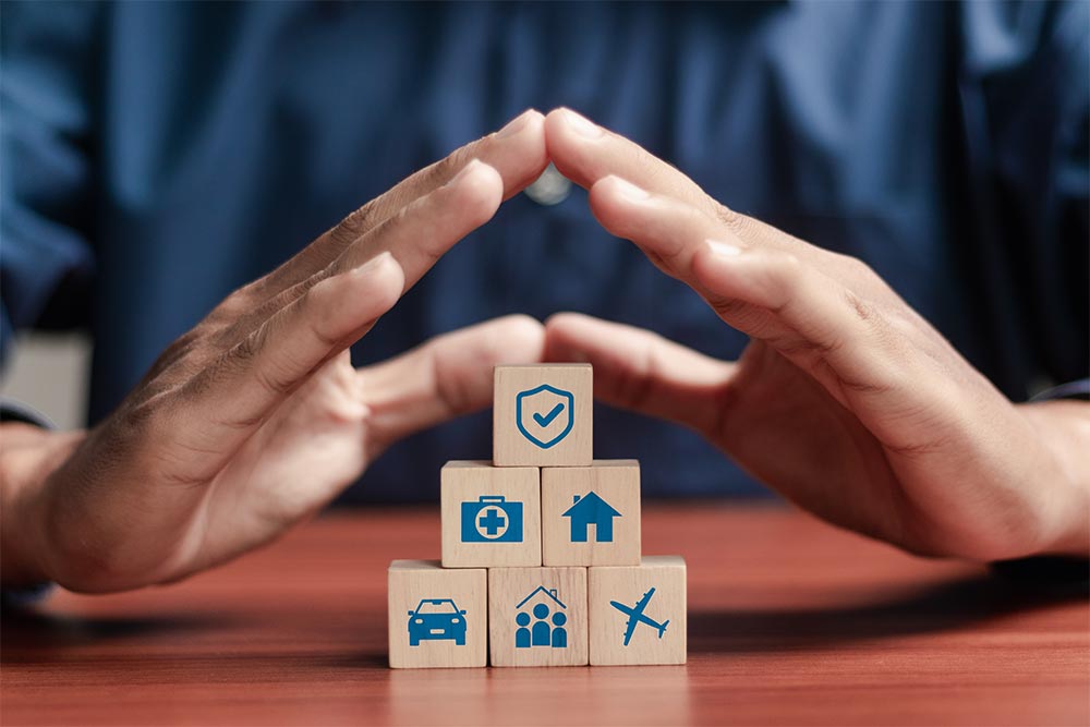 Insurance and assurance concept, Businessman protect wooden blocks with insurance icons for medical, life, car, home, travel insurance.