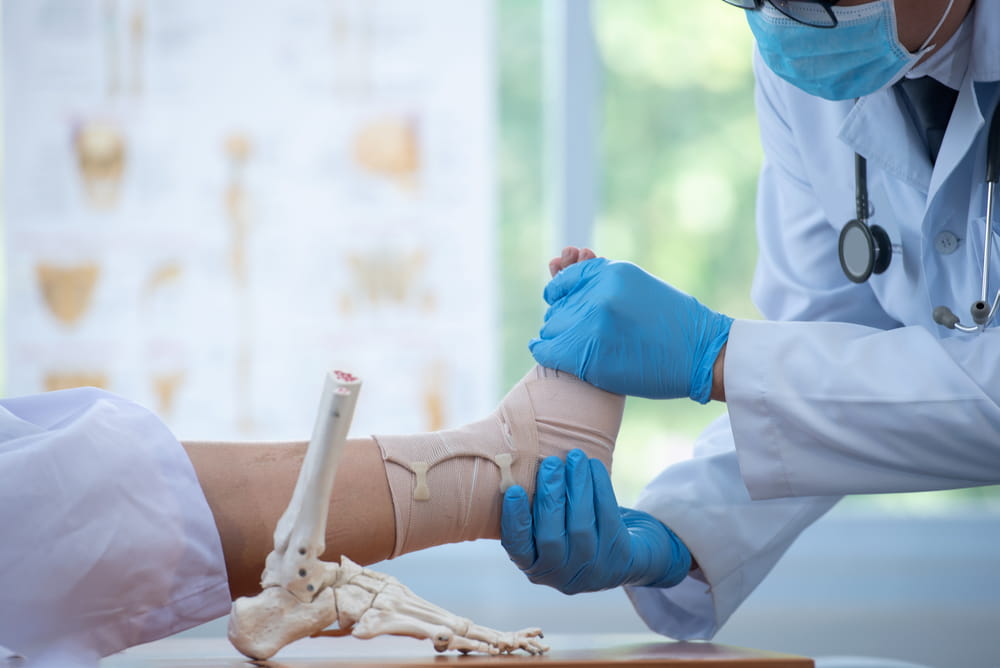 Doctor examining and training broken leg patient in hospital - physical therapy concept