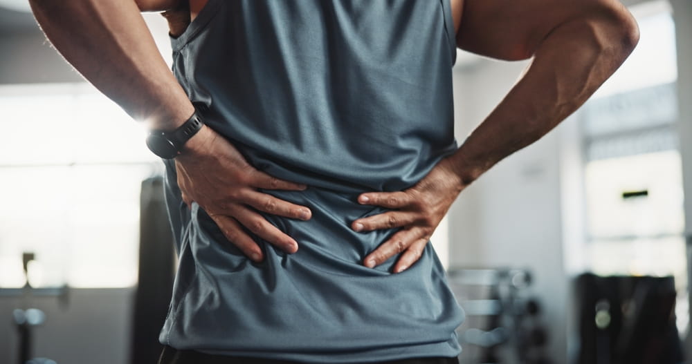 Man, hands and back injury with pain at gym for muscle tension, workout accident or sprain.