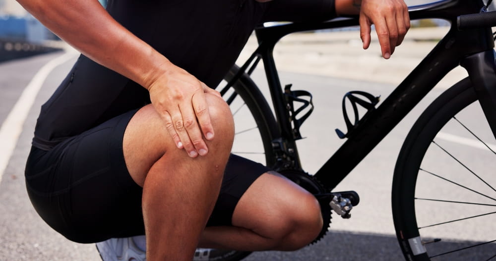 Knee pain, cyclist and hands with man in city for workout mistake, sports injury and fibromyalgia