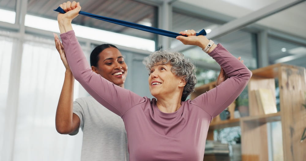Clinic, physio and old woman stretching with resistance band for rehabilitation, arthritis or help.