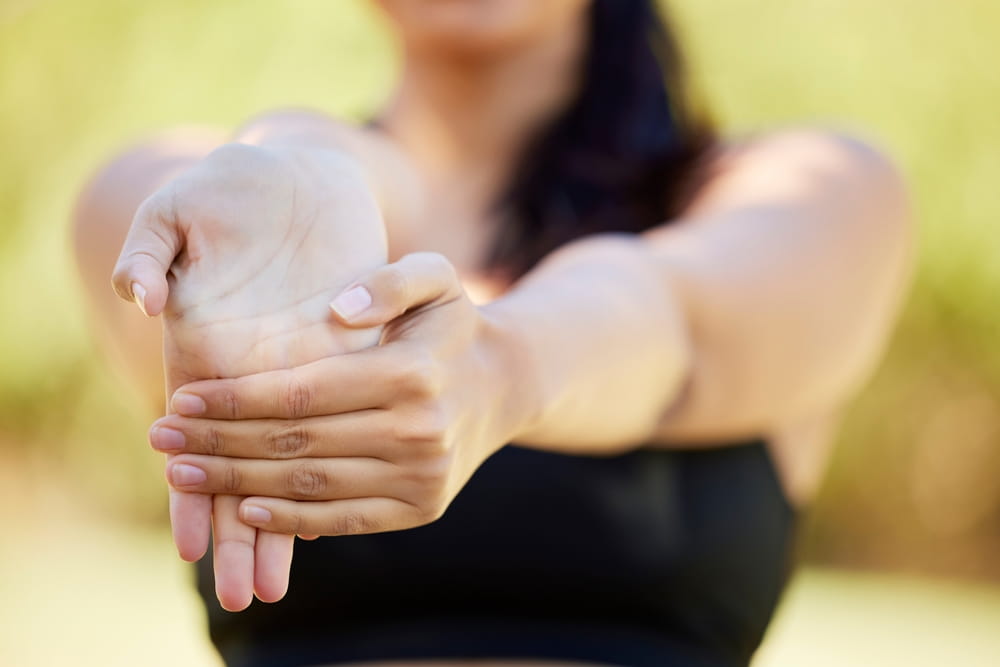 Closeup, hands and woman stretching in nature for fitness, yoga and cardio workout on blurred background.