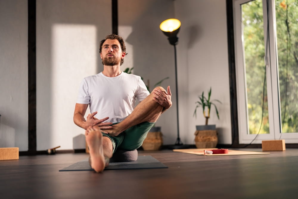 Yoga instructor practicing a variation of fire log pose - agnistambhasana - in a serene home studio, enhancing relaxation, flexibility, and mindfulness for overall wellbeing