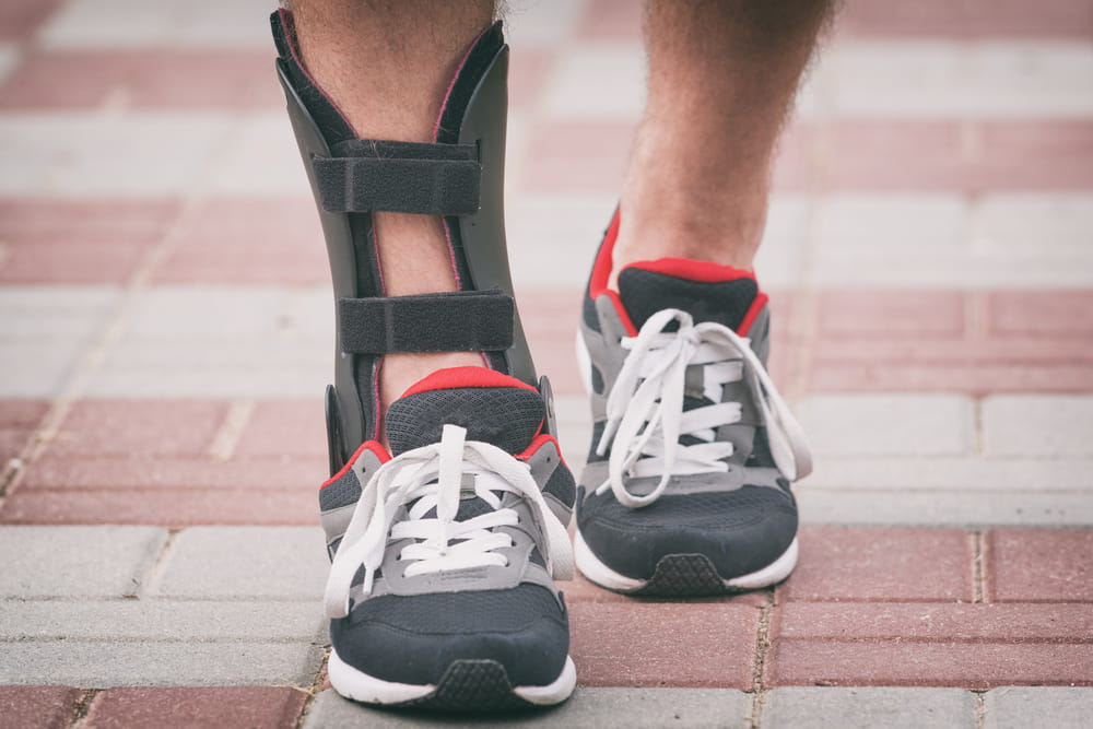 Man in athletic sneakers wearing ankle orthosis or brace