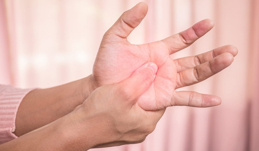Closeup of female holding her painful palm and numbness caused by prolonged work on the computer or housewife