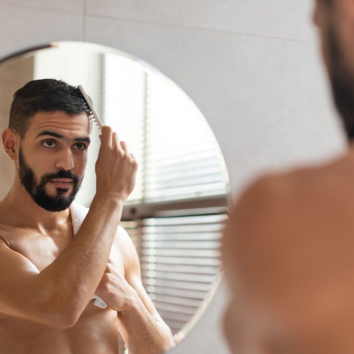 handsome young guy brushing his glossy hair