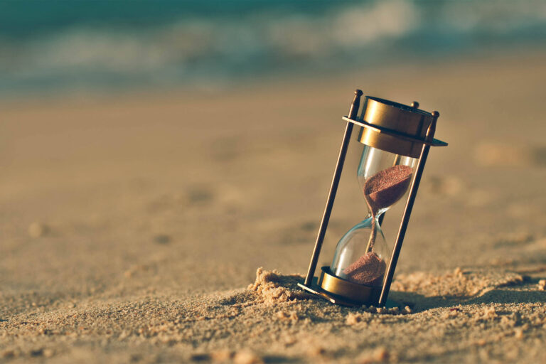 Hourglass on a sand dune beach. (vintage style)