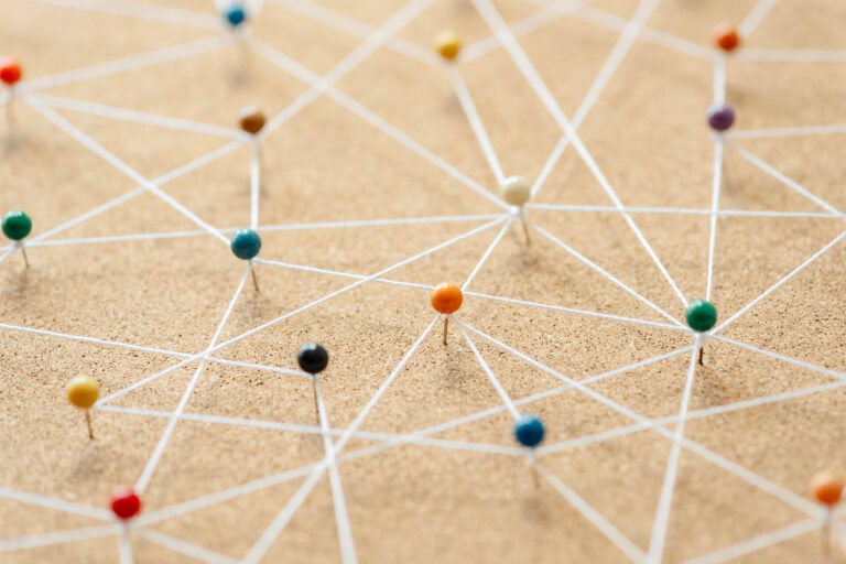 Colorful pins connected by string on a corkboard