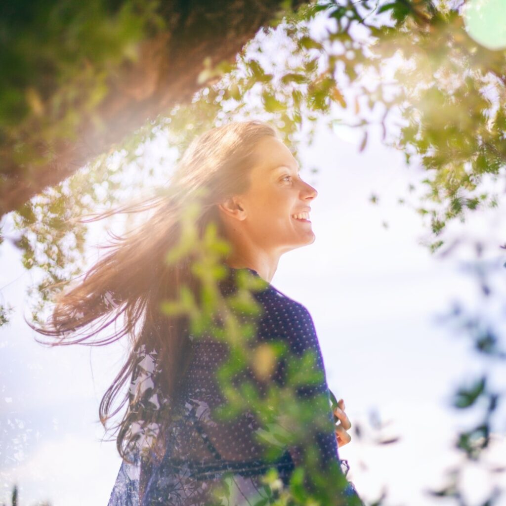 beautiful happy young woman in green tree branches