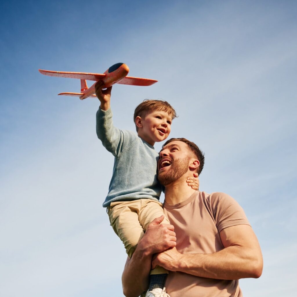 Father is holding son that playing with toy plane