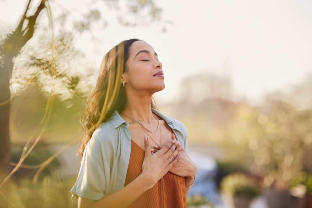 Young woman with hand on chest breathing in fresh air